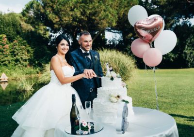 Taglio della torta, giardino di villa rosantica durante il matrimonio